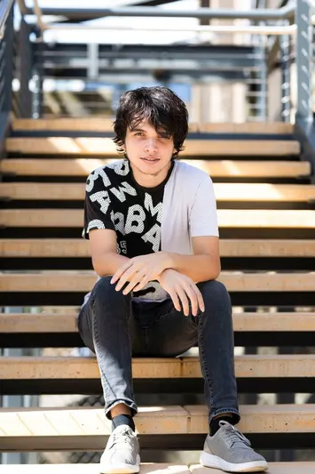 Ethan Fuhrmeister sitting on wooden stairs outdoors